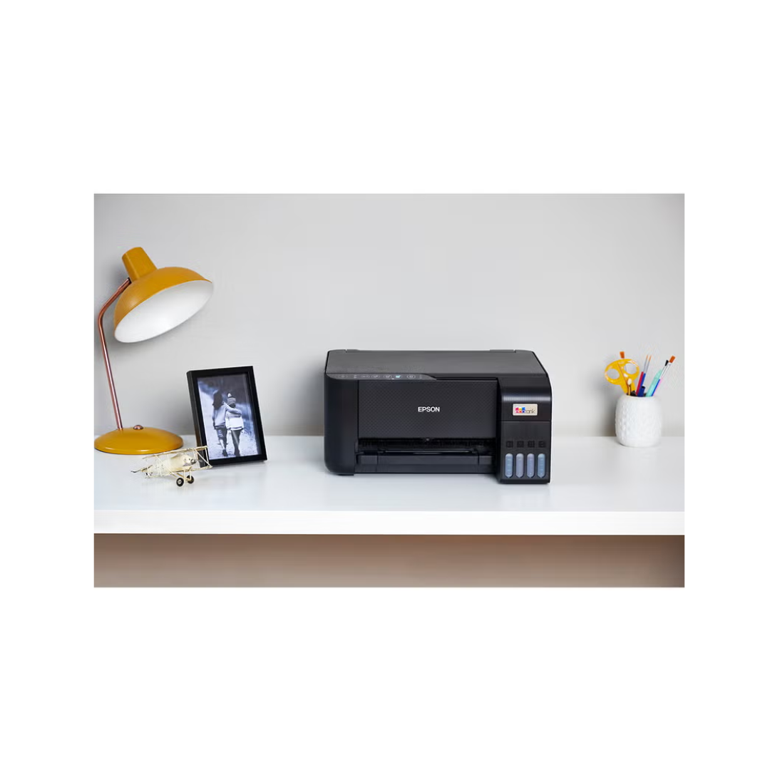 Epson printer on a desk with a lamp and photo frame in the background
